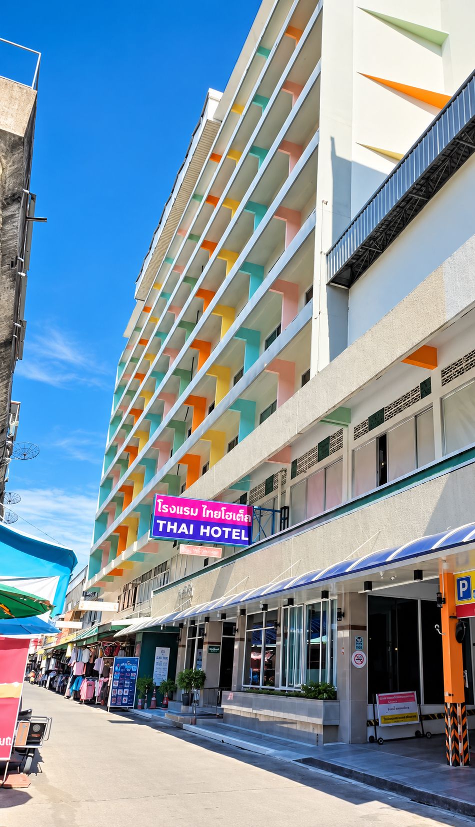Um hotel com vários andares, fachada colorida e placa indicando ser um hotel tailandês.
