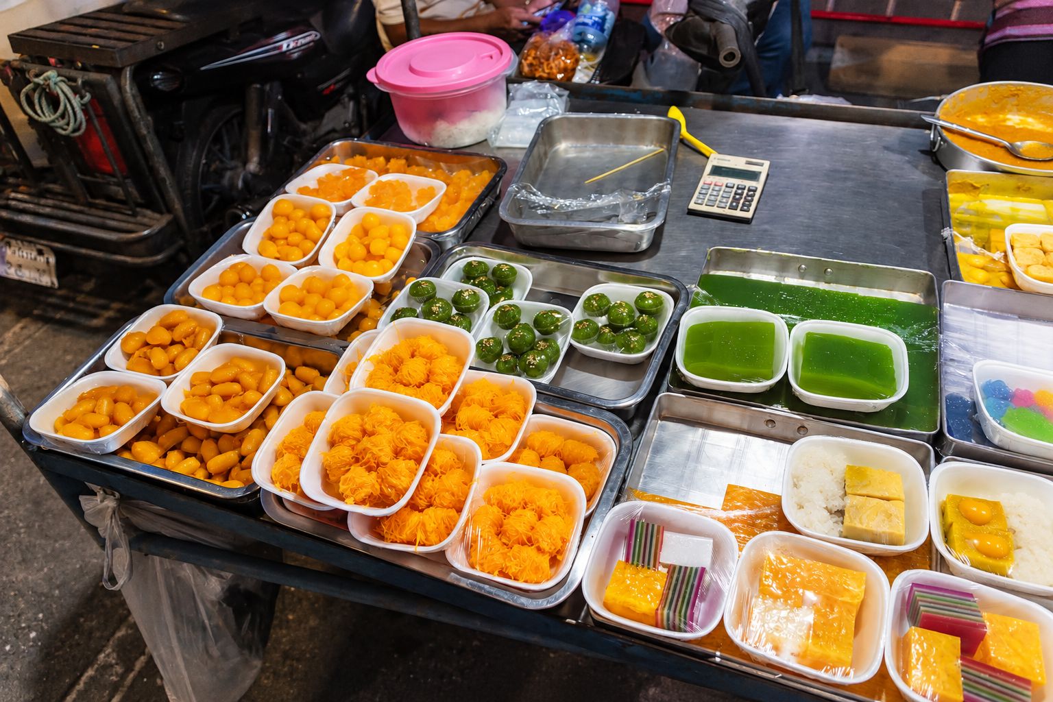 A variety of food items displayed on a metal table with trays and containers.