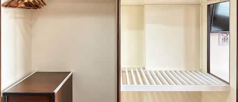 Une chambre avec une armoire, un petit bureau, un lit avec un matelas et des oreillers, et une paire de sandales sur le sol.