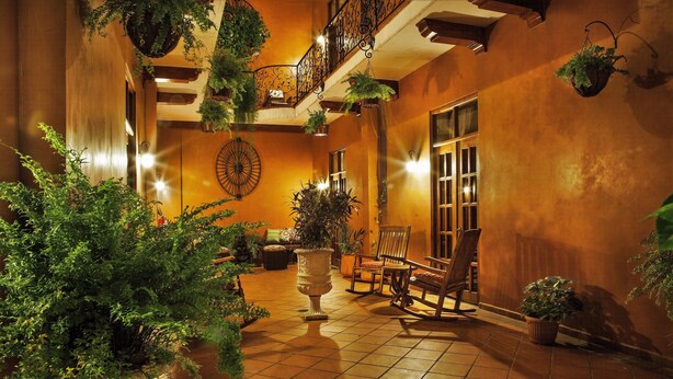 A spacious indoor courtyard with tiled flooring, multiple seating areas, and hanging plants. - La Isabela Suites (Panama City)