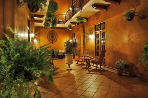 A spacious indoor courtyard with tiled flooring, multiple seating areas, and hanging plants. - La Isabela Suites (Panama City)