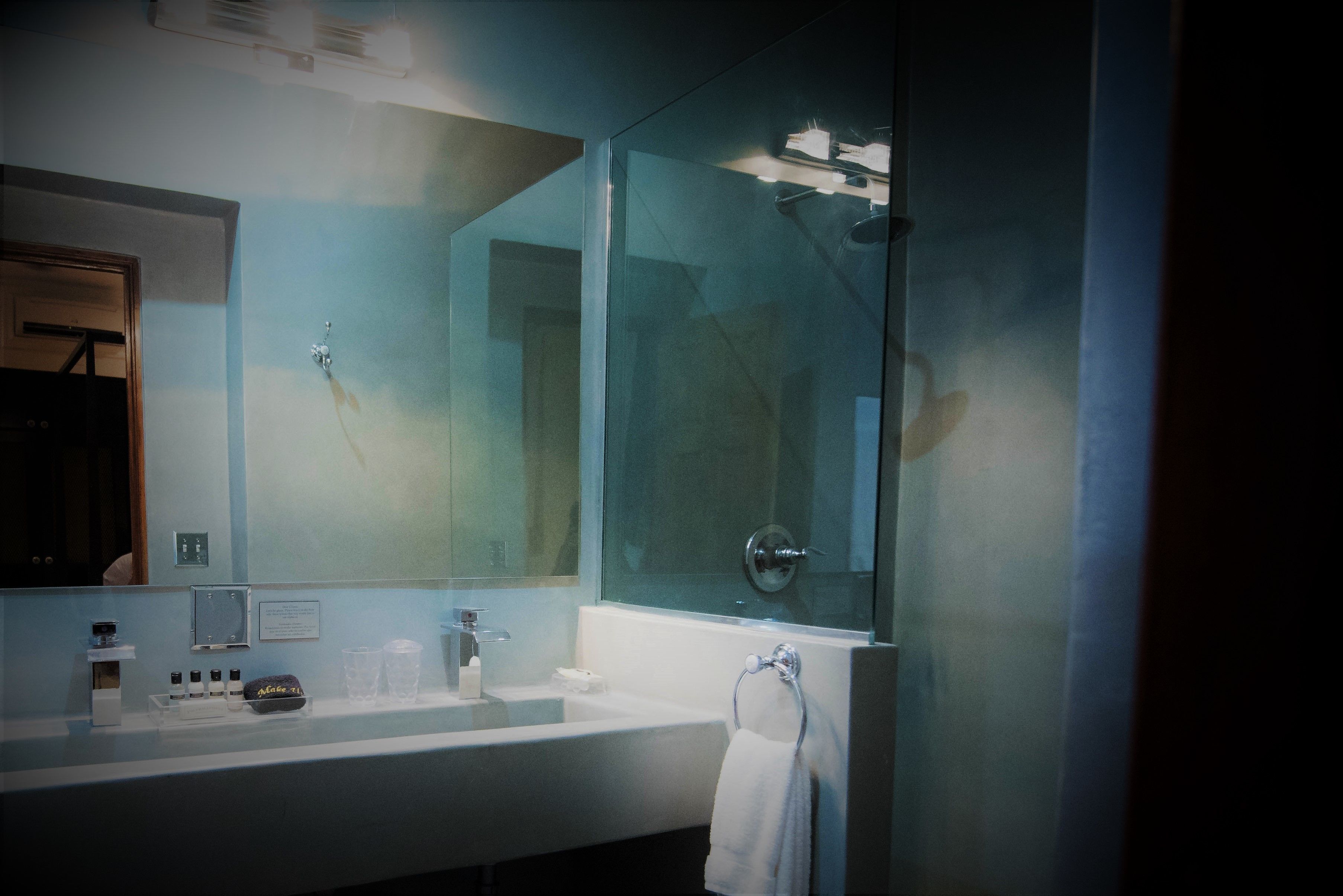 A modern bathroom with a large mirror, a white sink, and a glass shower enclosure.