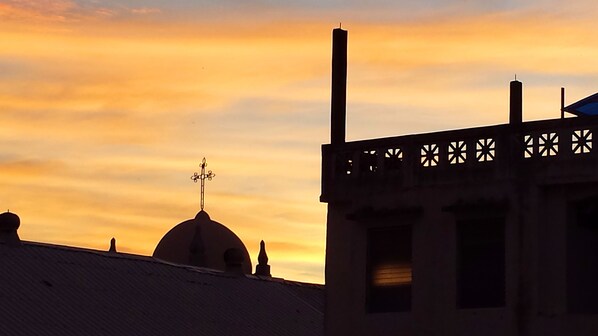 Silueta de un edificio con una cúpula y una chimenea contra un cielo al atardecer.