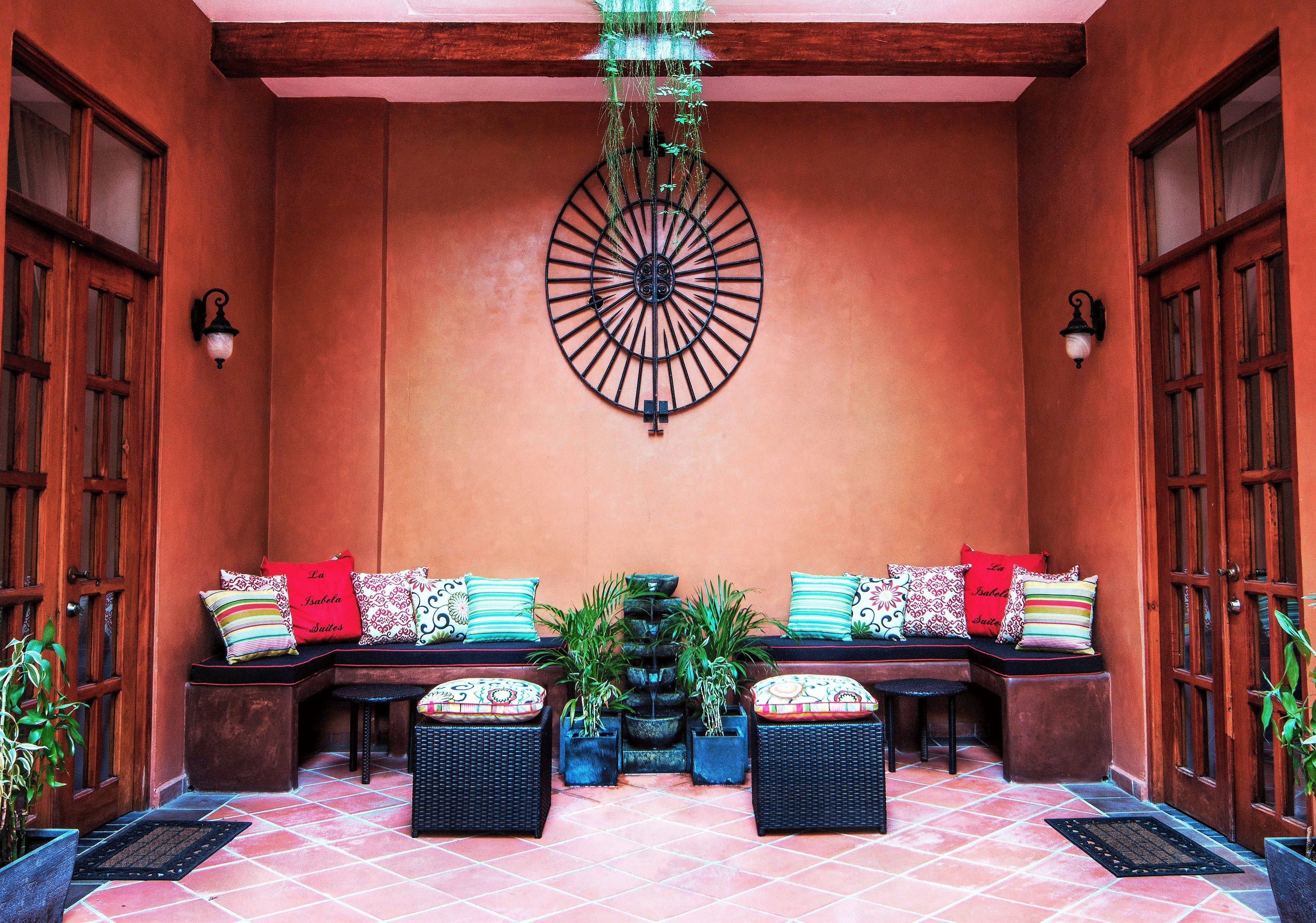 A cozy outdoor seating area with a central planter, benches with cushions, and a decorative metal wall piece.