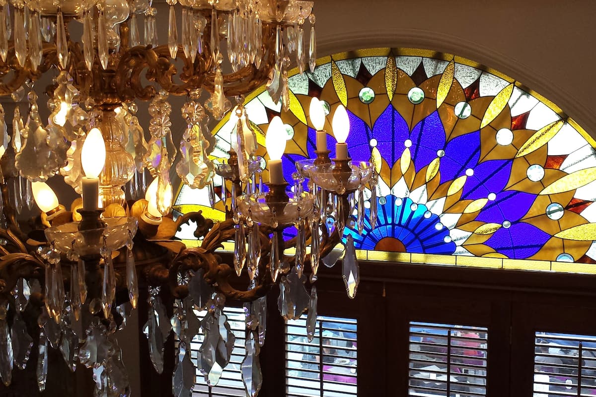 Un candelabro con adornos de cristal y un vitral con diseño en forma de abanico.