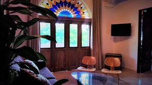 A room with a large window, a television mounted on the wall, and two chairs. - La Isabela Suites (Panama City)