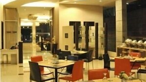 A modern dining area with tables and chairs, a curved ceiling, and a view into another room. - Andelir Hotel (Bandung)