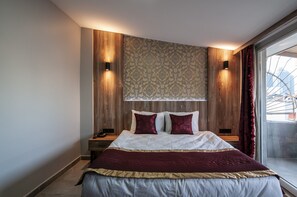 A modern bedroom with a large bed, wooden paneling, patterned wallpaper, and a view through a glass door. - Vali Konak Hotel (Istanbul)