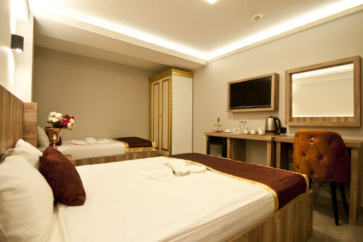 A hotel room with two beds, a desk, a TV, and a chair.