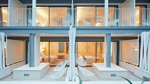 A modern hotel with a spacious outdoor seating area, a second-floor balcony with white railings, and a well-lit interior. - Hotel Omnium (Barcelona)