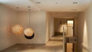 A modern hallway with two spherical hanging lights, a bench, and directional signs. - Hotel Omnium (Barcelona)