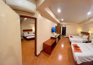 A hotel room with two beds, a TV, a desk, and a bathroom door. - Ban Chanchay (Hua Hin)