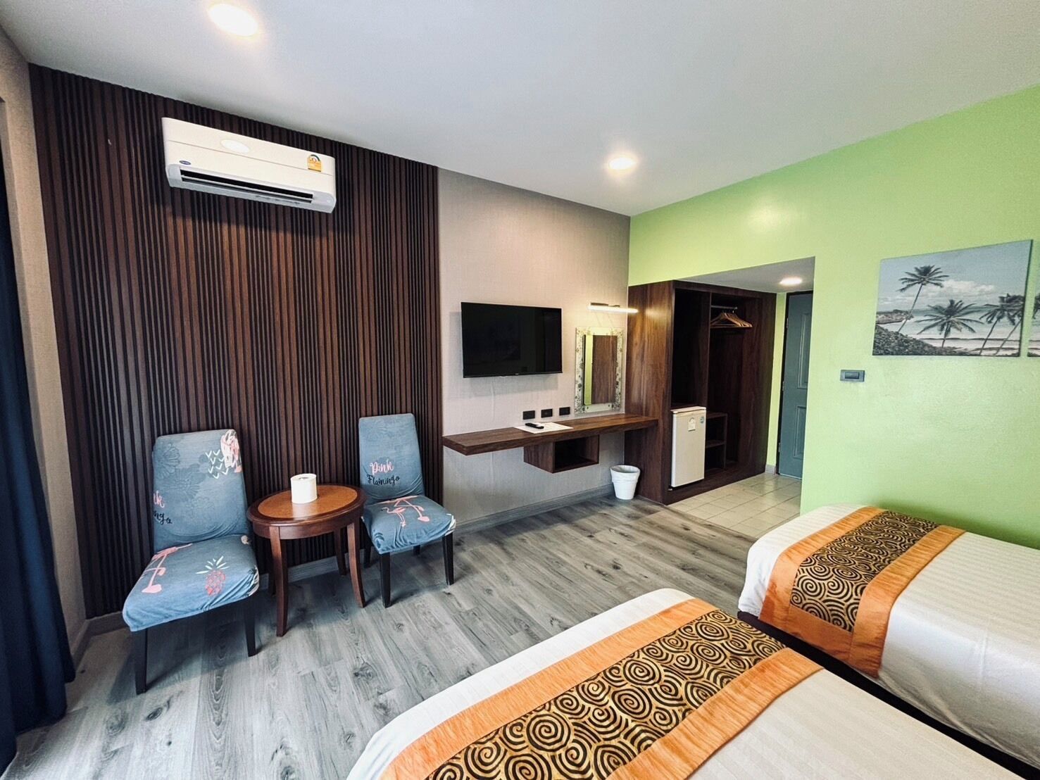 Quarto de hotel com duas camas, uma escrivaninha com cadeira, uma televisão e um ar condicionado.