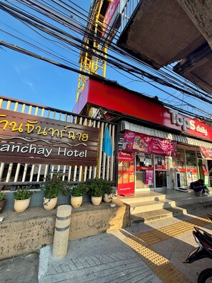 A hotel with a sign in a foreign language, a storefront with a red awning, and a motorcycle parked nearby. - Ban Chanchay (Hua Hin)
