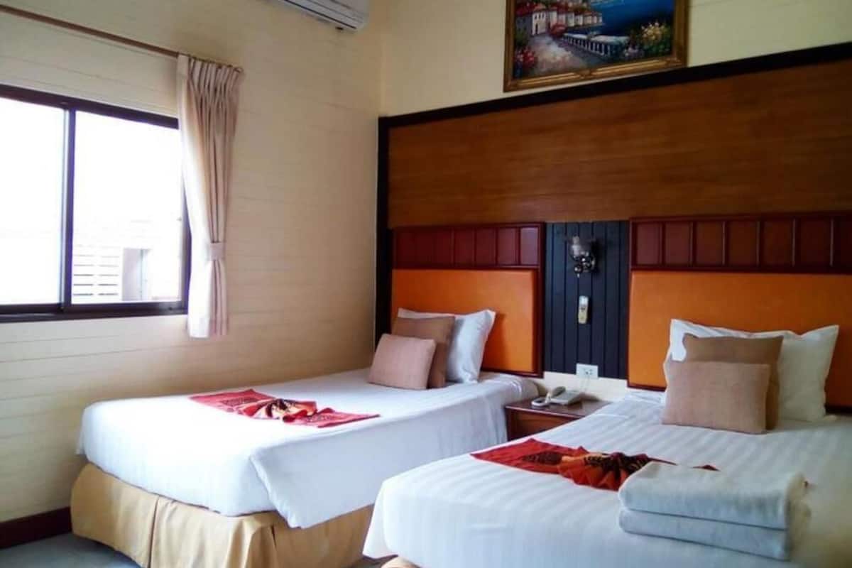 A hotel room with two beds, a window with curtains, a painting on the wall, and a wooden headboard.