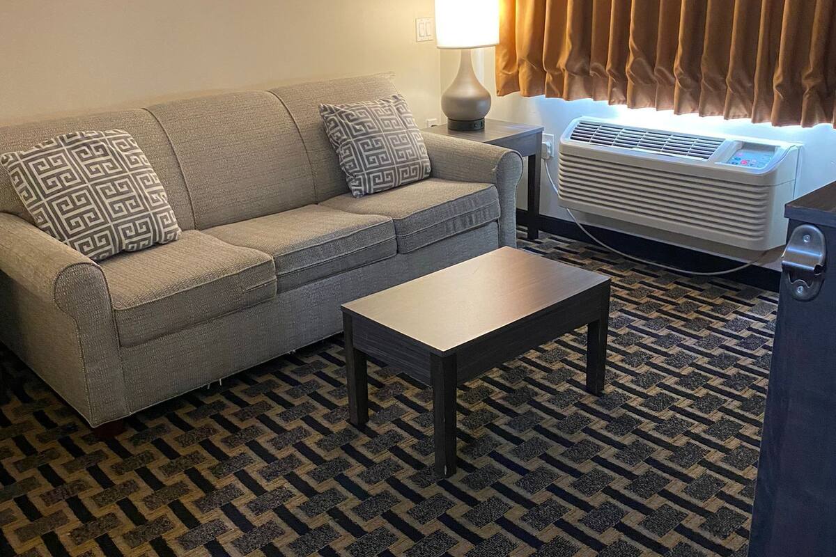 A living room with a sofa, a coffee table, a lamp, and an air conditioner.