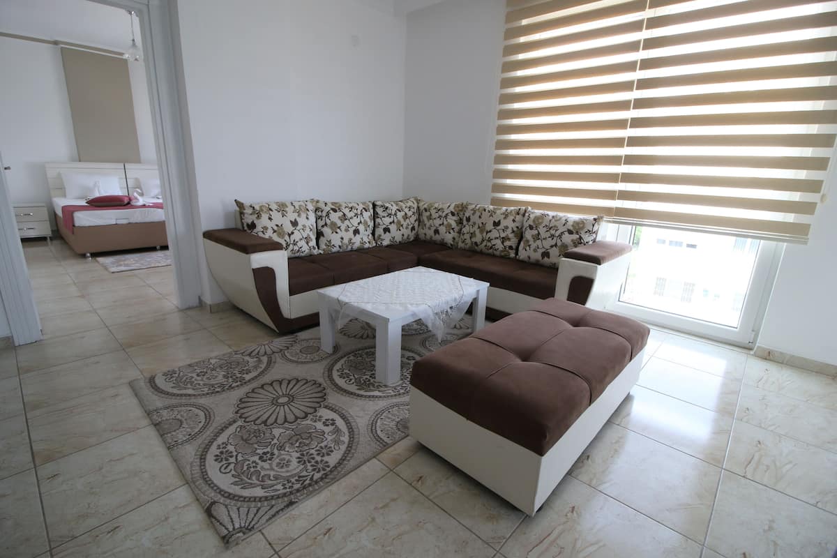 A living room with a sectional sofa, a small white table, and a patterned rug.