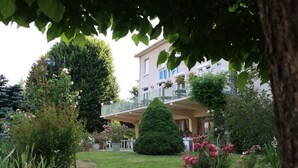 A hotel with a balcony, surrounded by well-maintained gardens and a variety of plants. - Le Chalet Fleuri (Chauvigny)