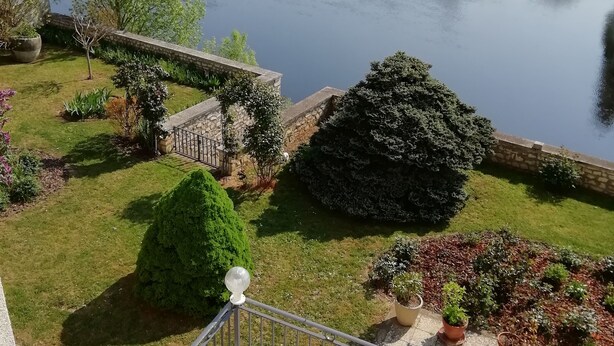 A balcony with a view of a river, a stone bridge, and a town in the background. - Le Chalet Fleuri (Chauvigny)
