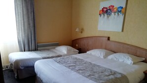 A hotel room with two beds, a wooden headboard, a painting of flowers on the wall, and a window with curtains. - Le Chalet Fleuri (Chauvigny)