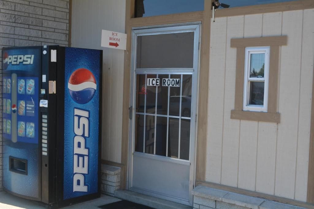 A building with an ice room sign, a Pepsi vending machine, and a small window.