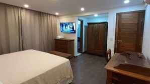 Une chambre d’hôtel équipée d’un lit, d’un bureau, d’une télévision et d’une armoire.