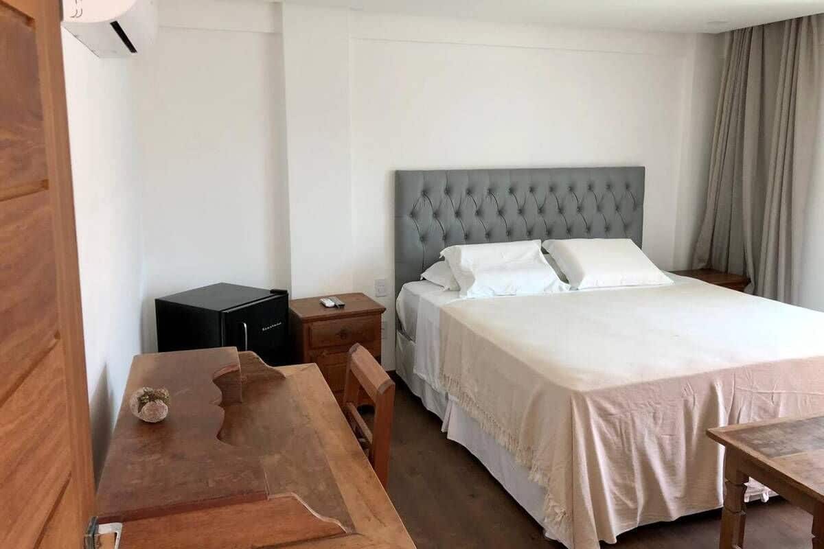 Una habitación de hotel con cama, una mesa de madera, una mesita de noche y una maleta negra.