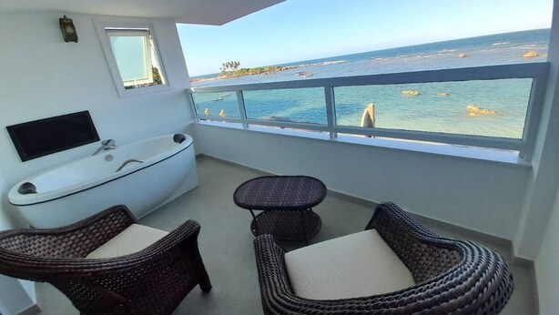 Un balcon avec des meubles en osier, une baignoire et une vue sur la mer.