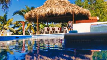 Una piscina al aire libre, sillones reclinables de piscina
