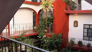 A multi-level building with balconies, red and white walls, and potted plants. - Cortizo Suites (San Miguel de Allende)