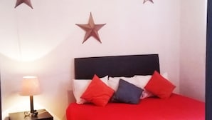 A bedroom with a bed, a nightstand, and three star decorations on the wall. - Cortizo Suites (San Miguel de Allende)
