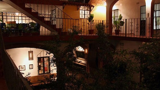 A multi-level interior with a staircase, balconies, and potted plants. - Cortizo Suites (San Miguel de Allende)