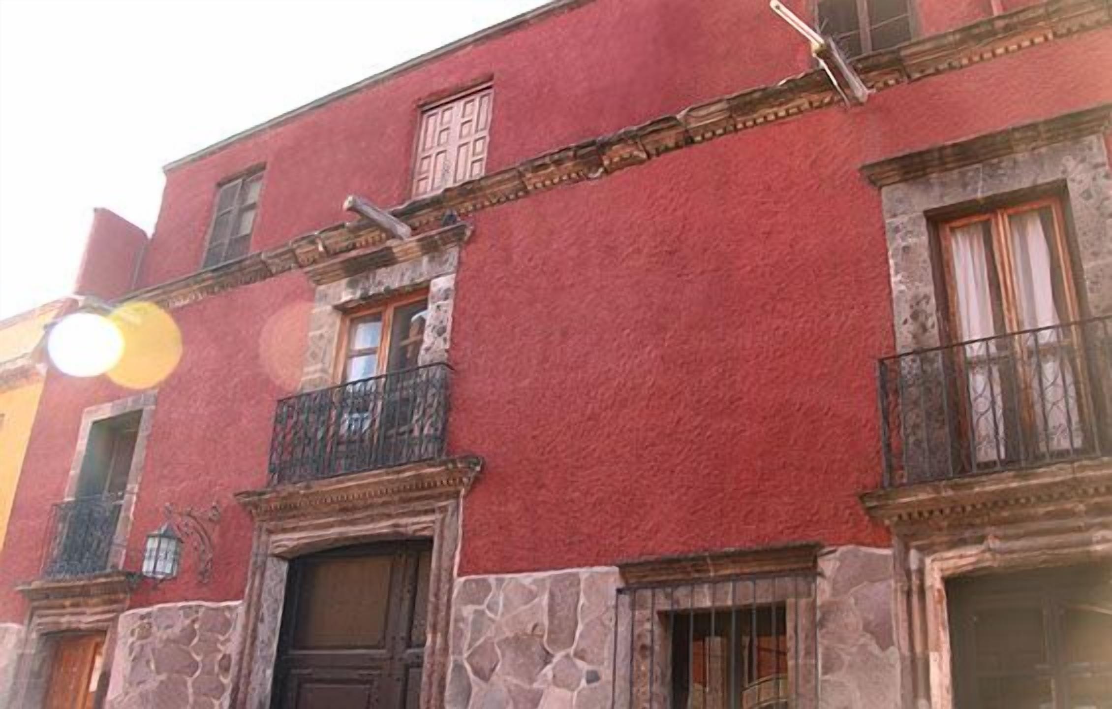 A red building with stone accents, multiple windows, and balconies.