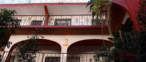 Un edificio de varios pisos con balcones, ventanas arqueadas y barandillas decorativas.