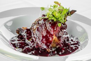 A dish with a berry sauce and greens on a white plate. - Greenhill Hotel (Wigton)