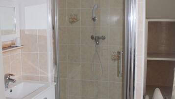 A bathroom with a glass-enclosed shower, a white sink, and a mirror.
