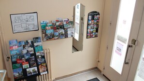 A hallway with a bulletin board displaying various travel brochures and a map. - Beausejour Hotel (Chauvigny)