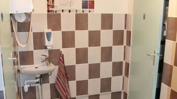 Ein Badezimmer mit Waschbecken, einem aufgehängten Handtuch und einer Tür.