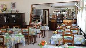 A dining area with multiple tables, chairs, and a bar area with shelves of bottles and glasses. - Beausejour Hotel (Chauvigny)