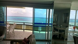 A balcony with a view of the ocean, wicker furniture, and a glass table. - Kristhal Plaza (San Andrés)
