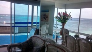 A balcony with a view of the ocean, wicker furniture, and a vase with flowers. - Kristhal Plaza (San Andrés)