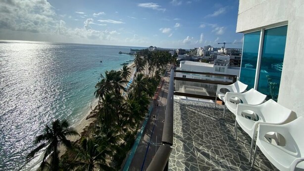 A view of a beach with a pool and lounge chairs, overlooking the ocean. - Kristhal Plaza (San Andrés)