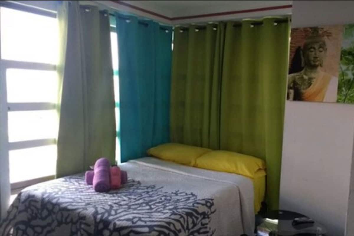 A room with a bed, curtains, a painting, and a window.