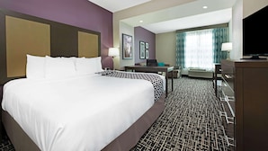 A hotel room with a large bed, a desk, a chair, a television, and a window with curtains. - La Quinta Inn & Suites by Wyndham Lake Charles - Westlake (Westlake)
