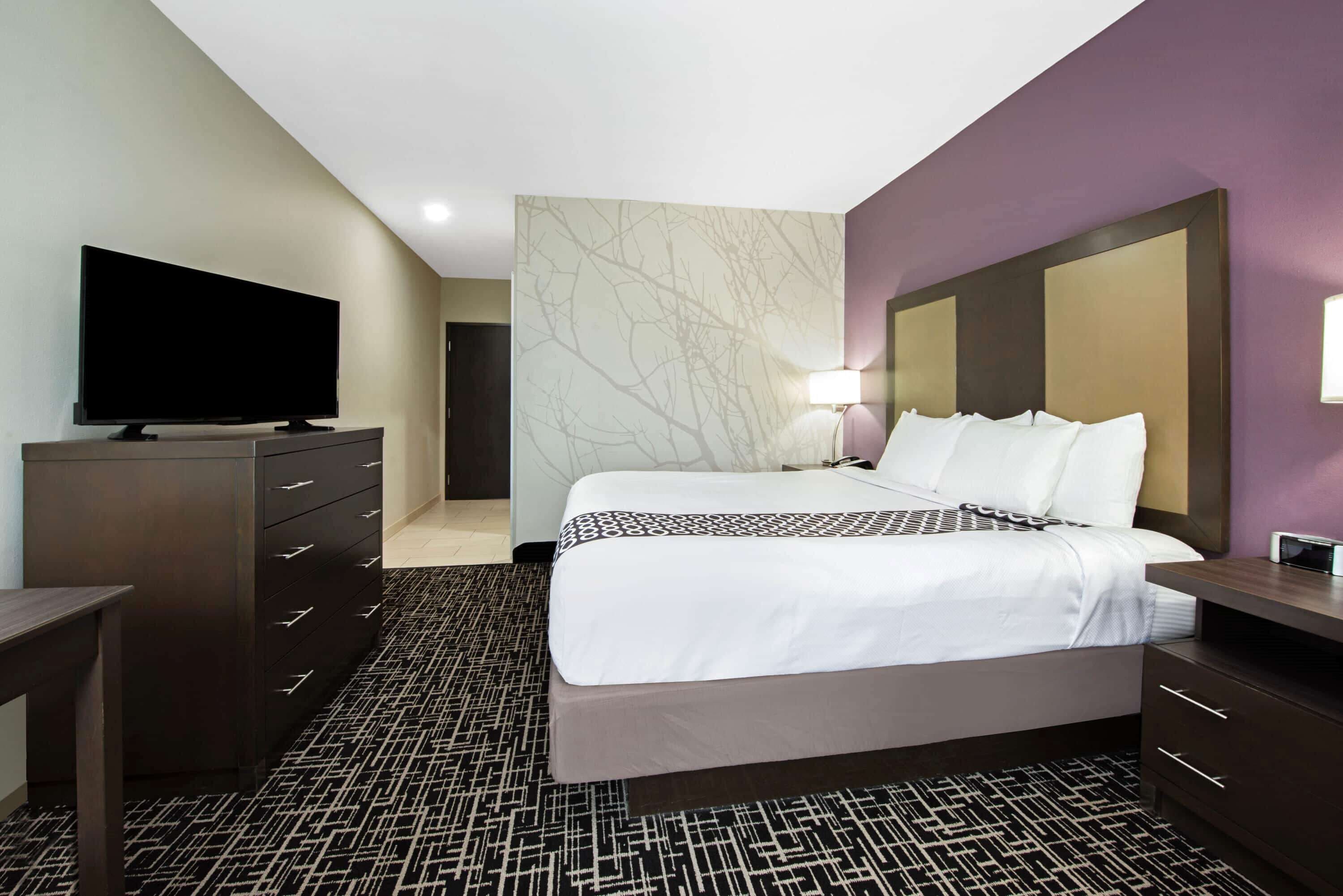 Een hotelkamer met een groot bed, een flatscreen televisie, een dressoir en een bureau.