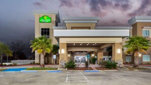 A La Quinta Inn & Suites with a modern design, a parking lot, and palm trees. - La Quinta Inn & Suites by Wyndham Lake Charles - Westlake (Westlake)