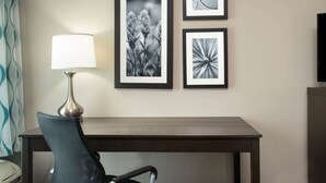 A hotel room with a desk, a chair, and three framed pictures on the wall. - La Quinta Inn & Suites by Wyndham Lake Charles - Westlake (Westlake)