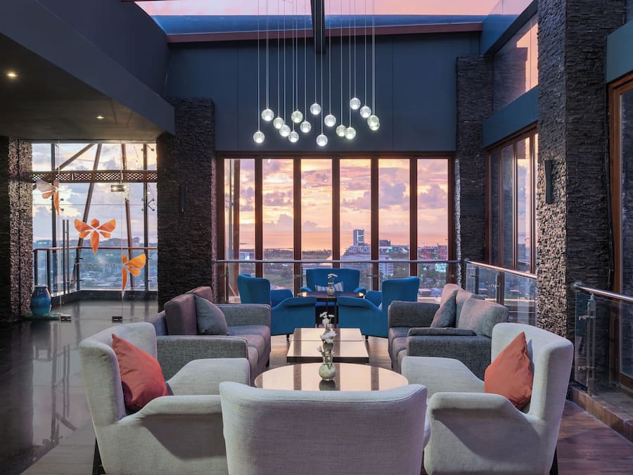 Eine moderne Lounge mit bequemen Sitzmöglichkeiten, einem zentralen Tisch und großen Fenstern mit Blick auf die Stadt.