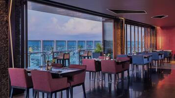 Un restaurante moderno con vistas panorámicas de la ciudad, amplios ventanales y mobiliario contemporáneo.