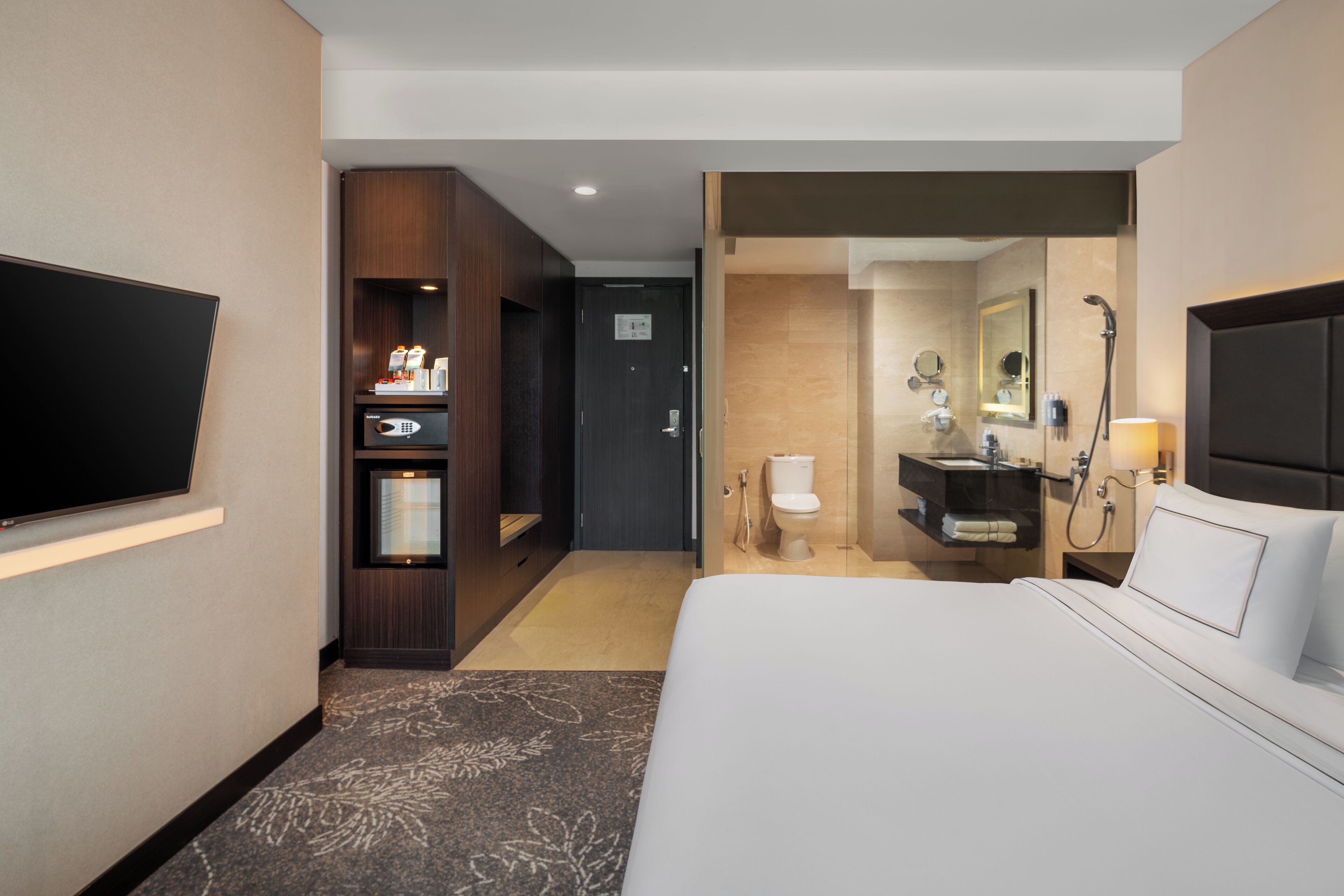 Camera d'albergo con un letto grande, una TV a schermo piatto montata a parete, un minibar, un bagno con doccia e un WC.